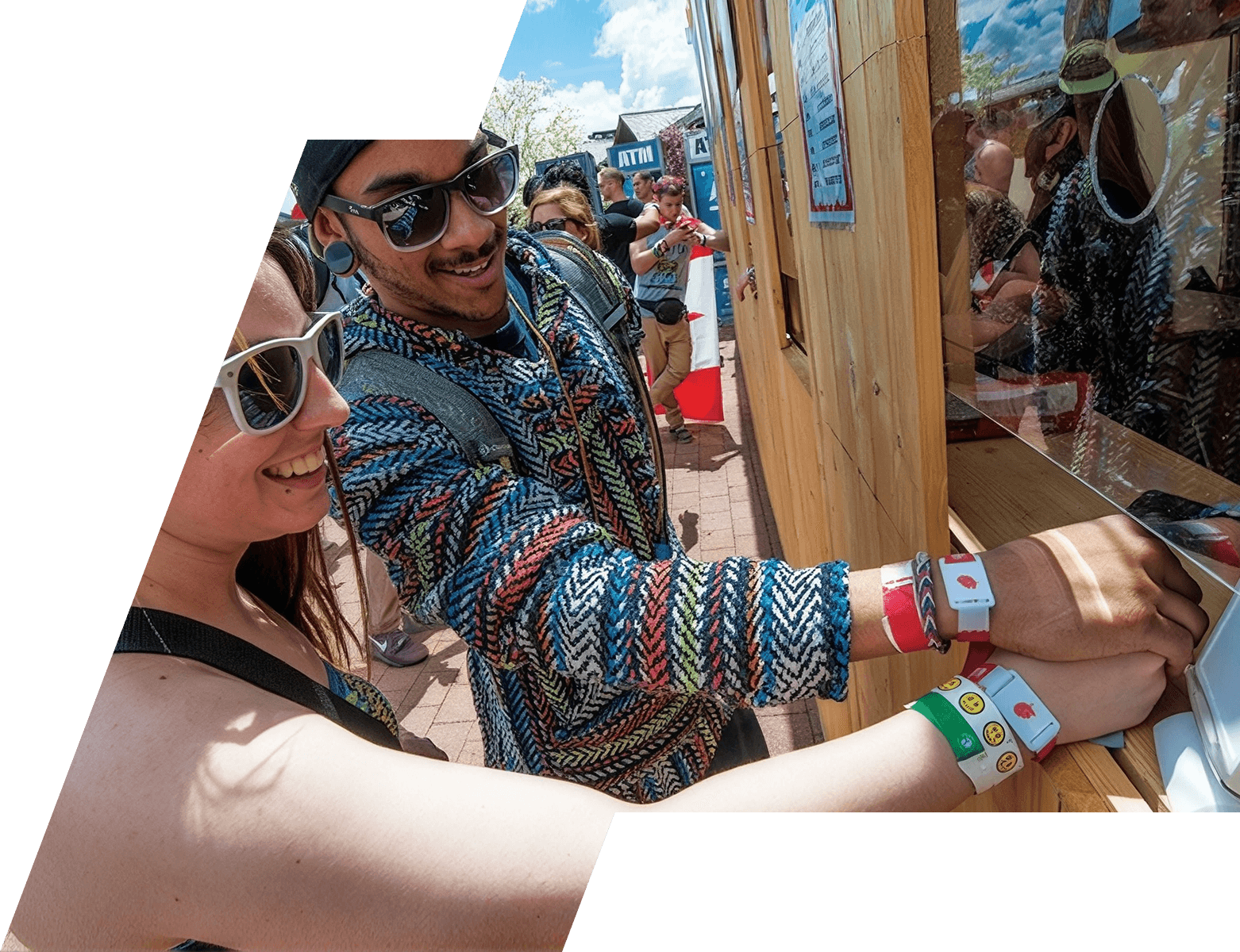 Festival-goers tapping NFC wristbands at a cashless payment booth on a sunny day