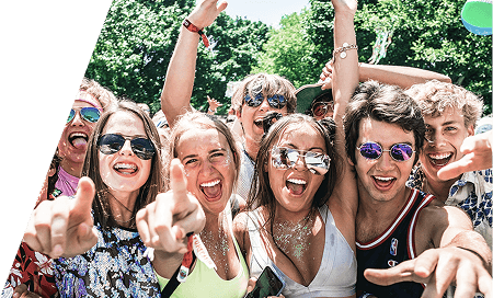 Group of young festivalgoers in sunglasses celebrating with arms raised