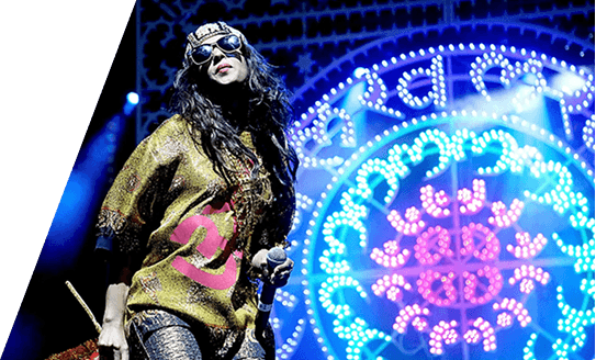 Performer on stage backed by a bright blue circular light installation