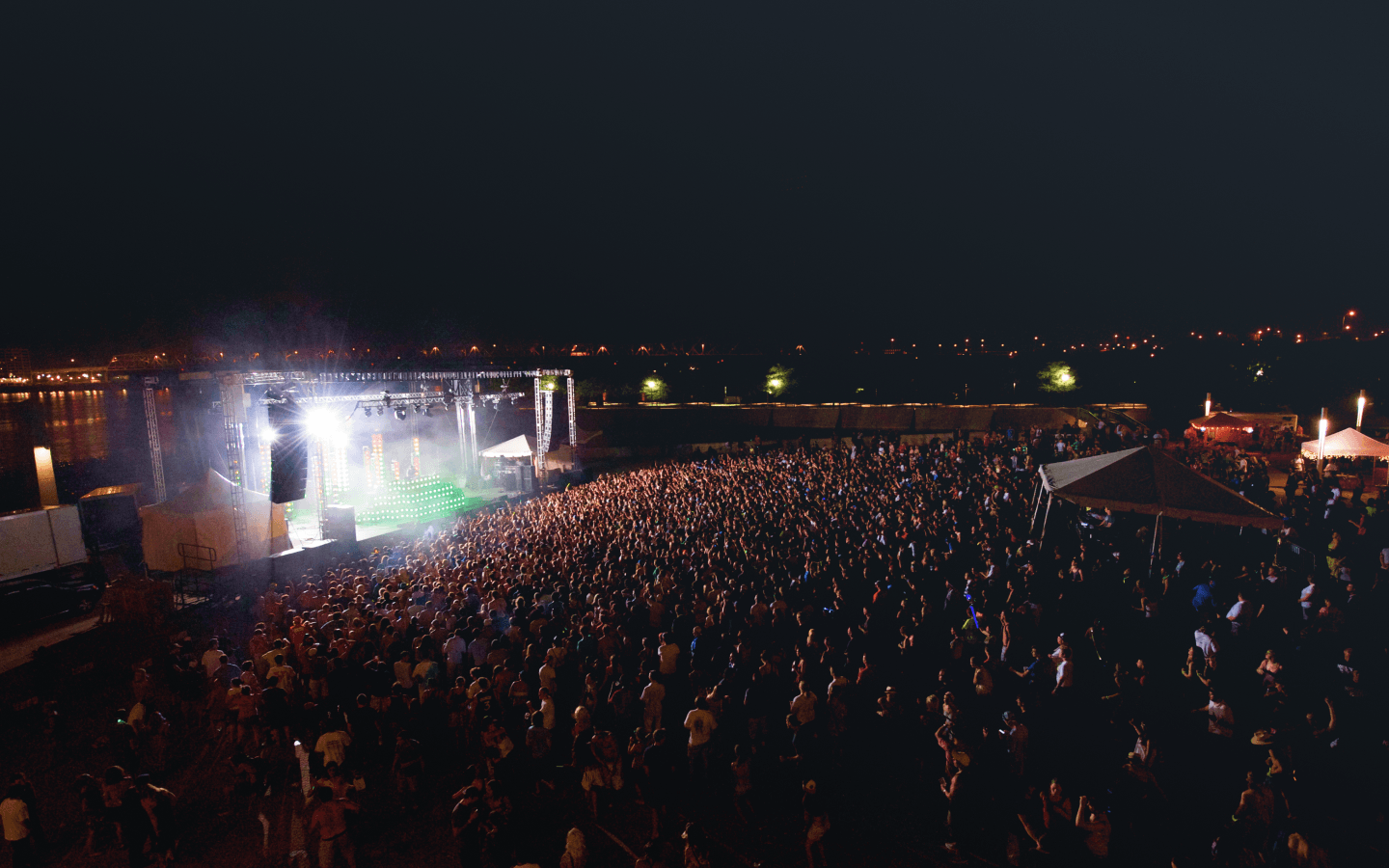 Festival main stage at night with packed crowd along the waterfront