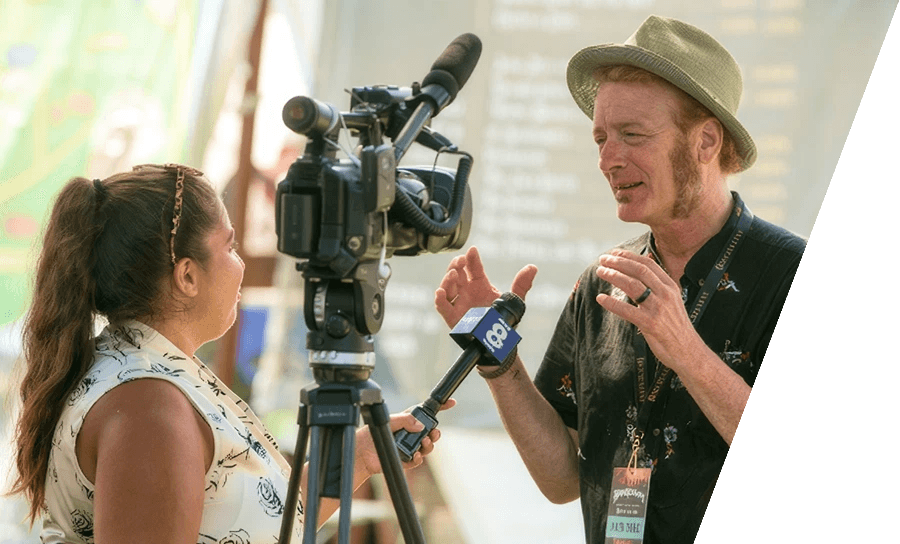 Television reporter interviewing a festival attendee with a camera and microphone