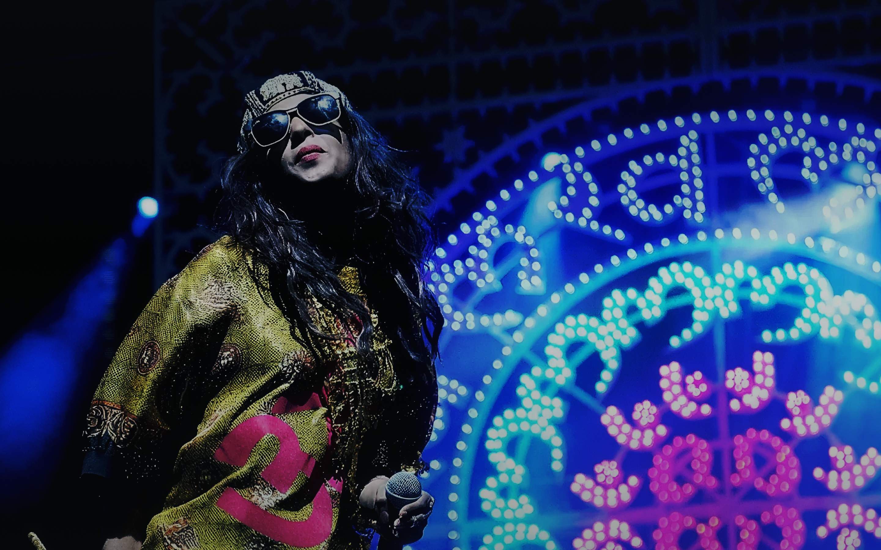 Festival performer in sunglasses on a vividly lit main stage