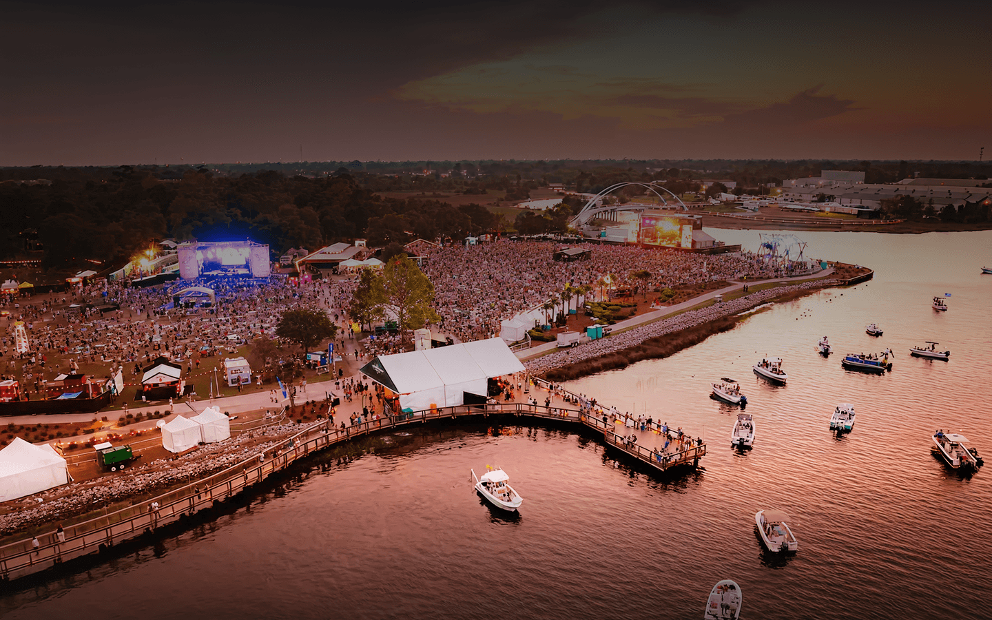 Aerial view of High Water Festival with stages along the waterfront at sunset
