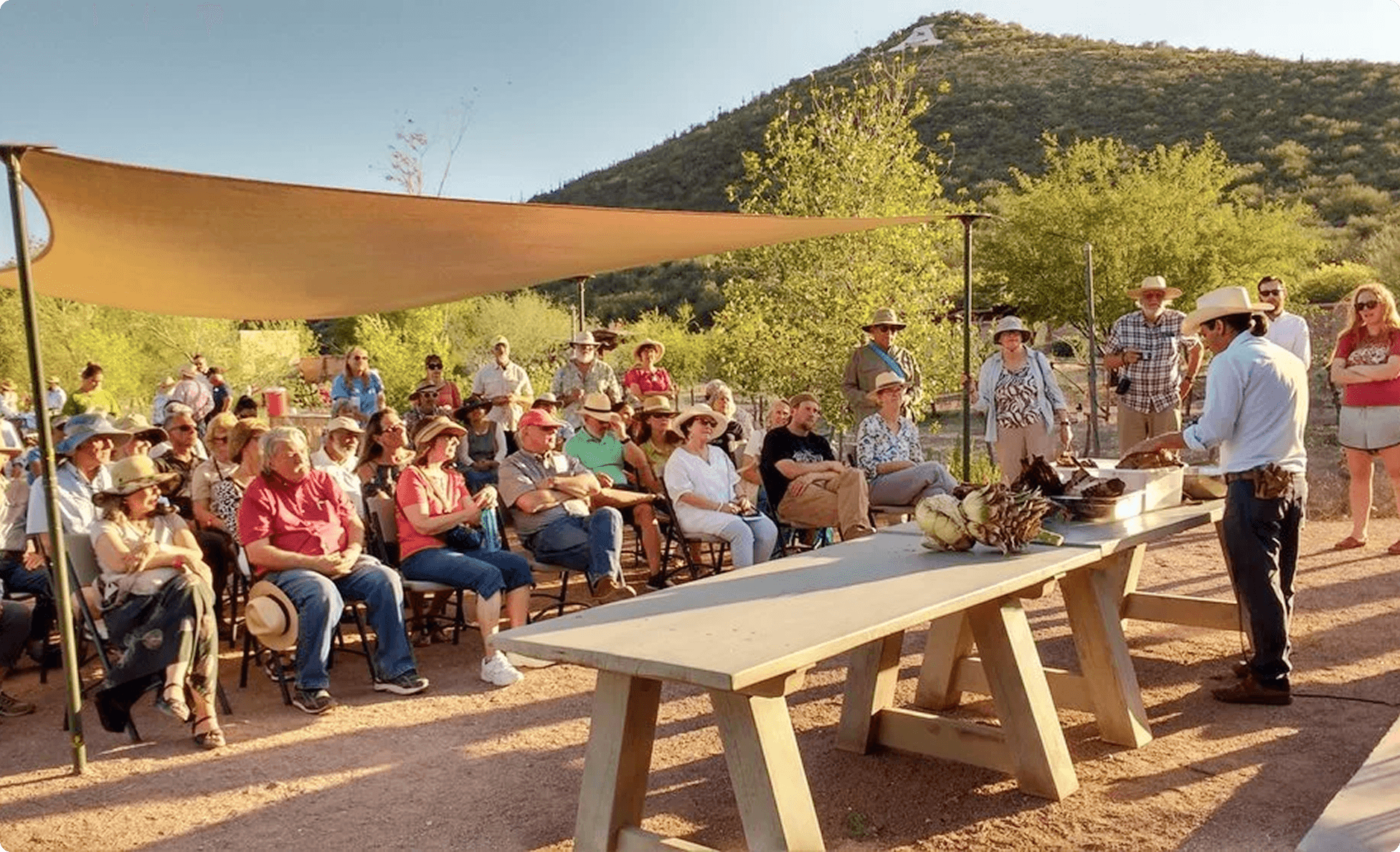 Open-air culinary demonstration with a seated crowd in the high desert