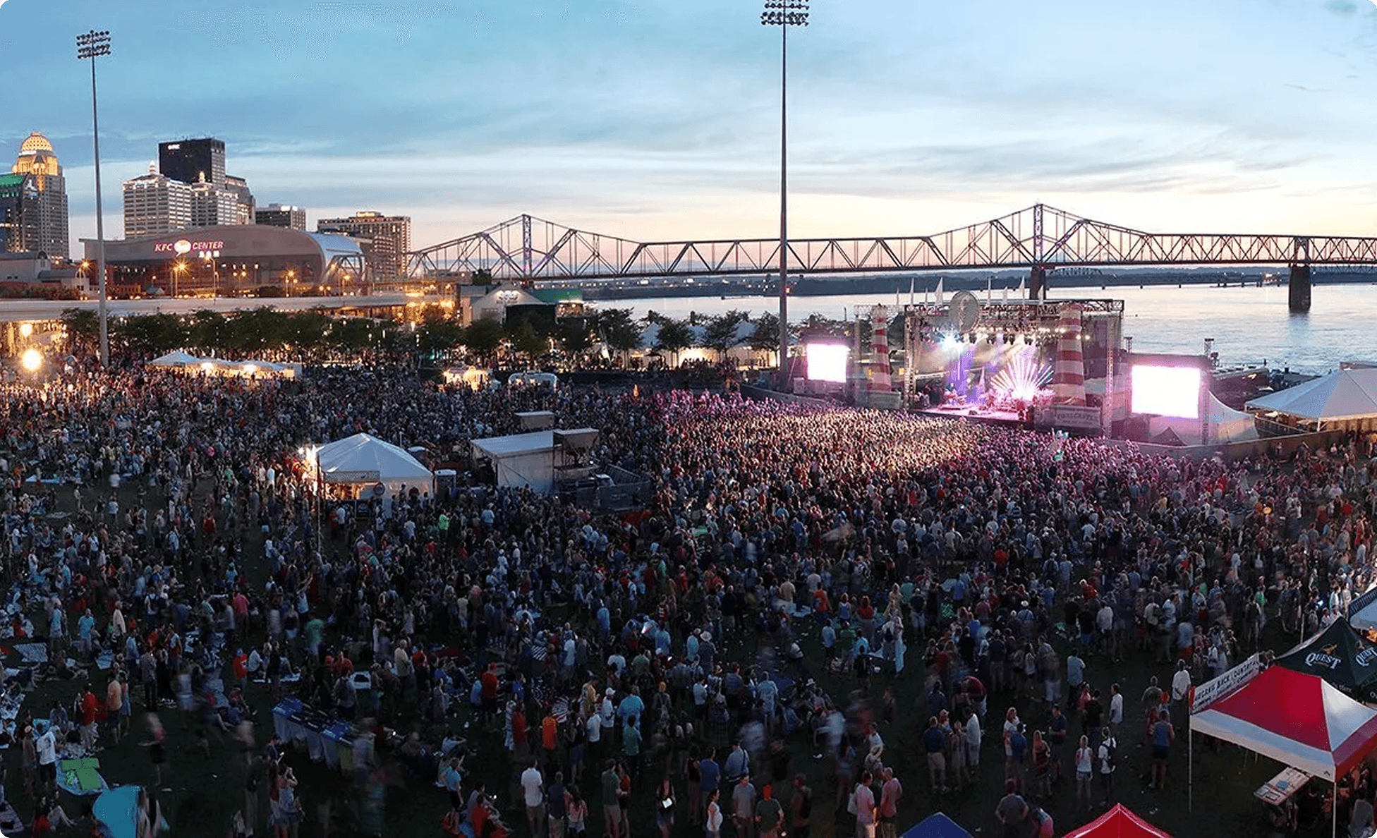 Thousands watching the main stage along the river at dusk
