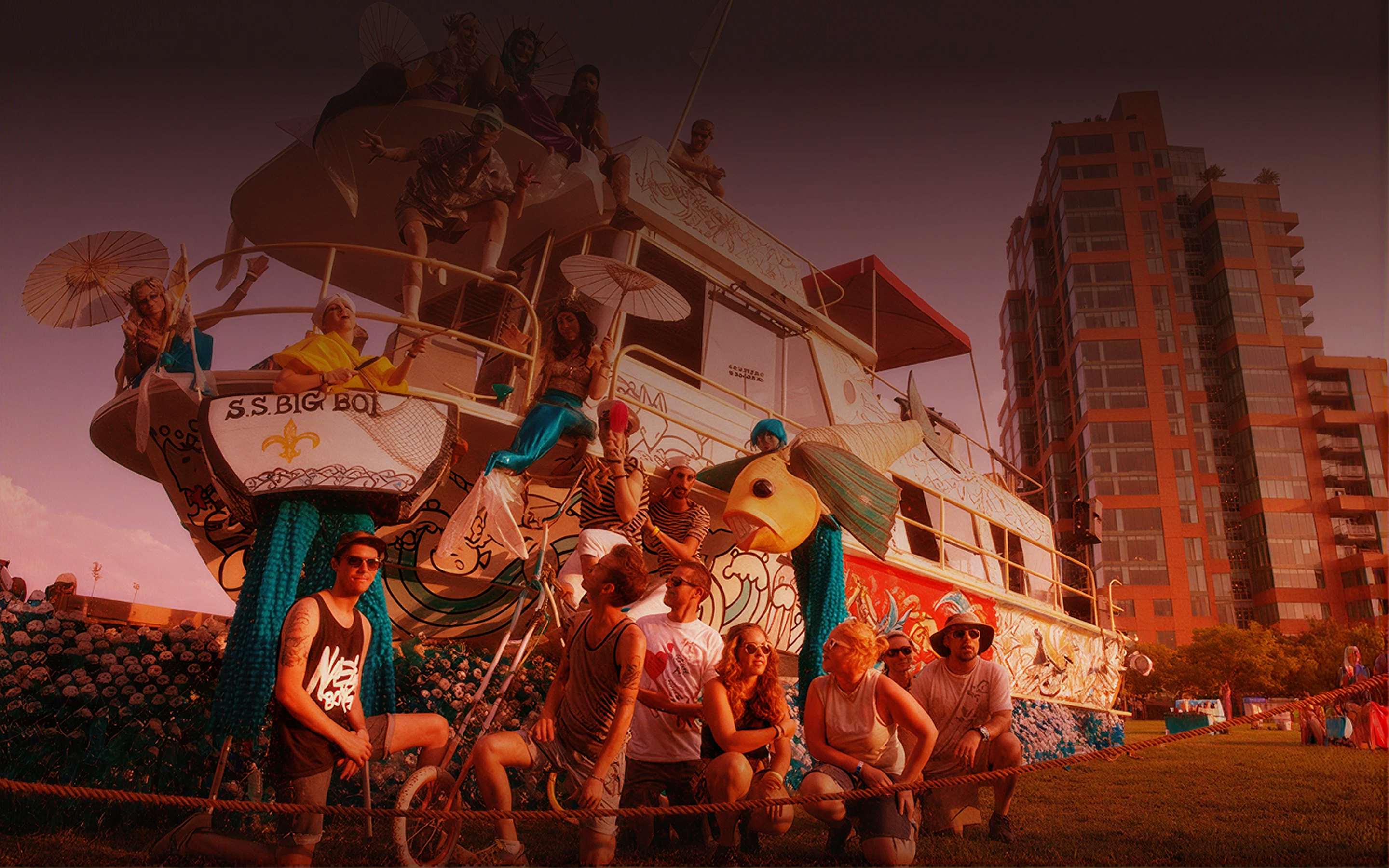 Costumed festival performers on a decorated art-boat float at golden hour with a crew posed in front