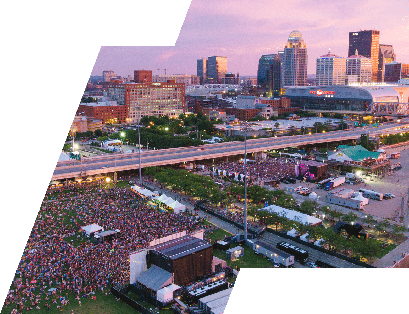 Aerial view of a festival crowd with the Louisville skyline at dusk